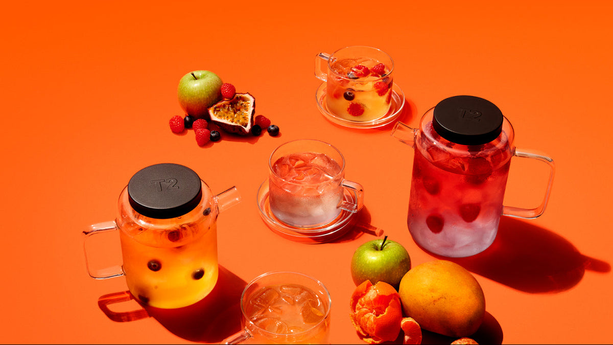 Assorted glasses with fruits and drinks on an orange background